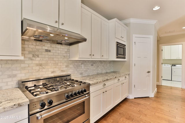1505 W Orangewood Ave W, Phoenix, AZ 85021 - kitchen featuring stainless steel appliances, under cabinet range hood, washer and dryer, ornamental molding, and white cabinets