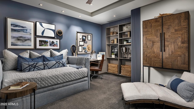 bedroom featuring a raised ceiling, ceiling fan, and dark colored carpet