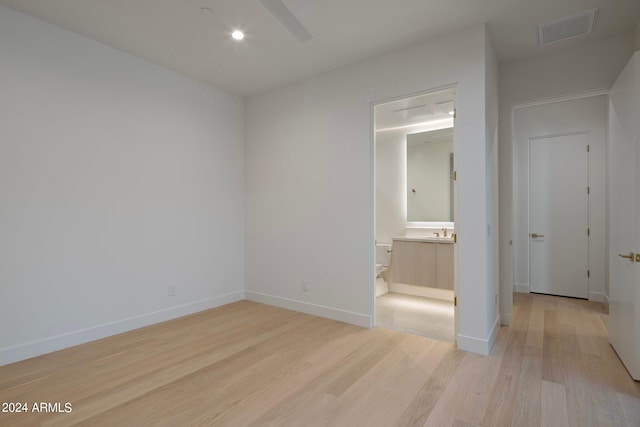 unfurnished bedroom with ensuite bathroom and light hardwood / wood-style flooring