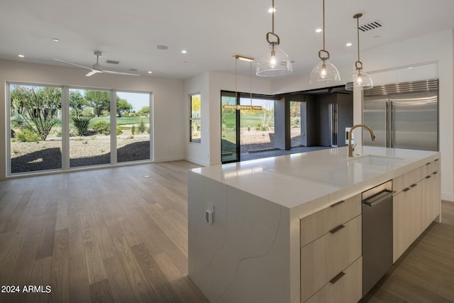 kitchen featuring hanging light fixtures, appliances with stainless steel finishes, hardwood / wood-style flooring, sink, and ceiling fan