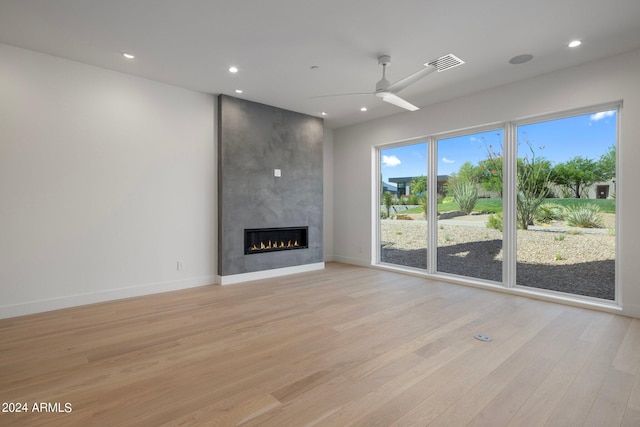 unfurnished living room with ceiling fan, light hardwood / wood-style flooring, and a fireplace