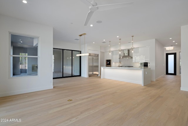 unfurnished living room with ceiling fan, light hardwood / wood-style floors, and sink