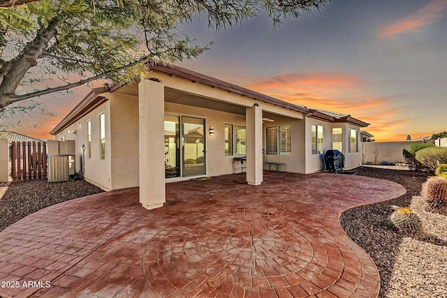 back house at dusk featuring cooling unit and a patio area