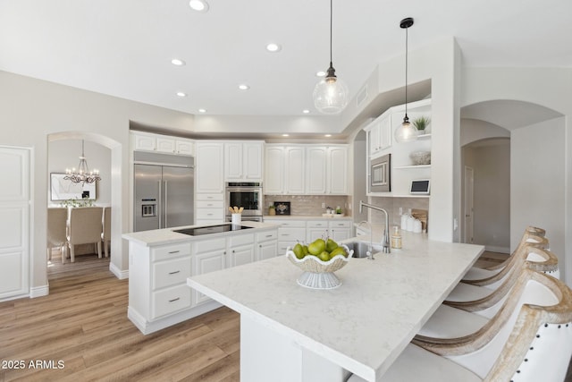 kitchen with built in appliances, a peninsula, arched walkways, and a sink