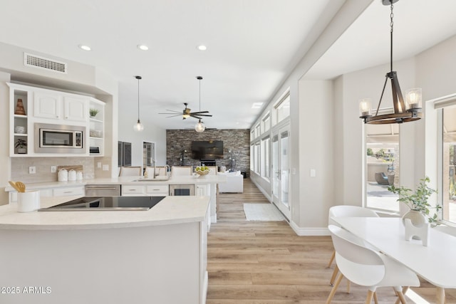 kitchen with open shelves, visible vents, a healthy amount of sunlight, a sink, and a peninsula