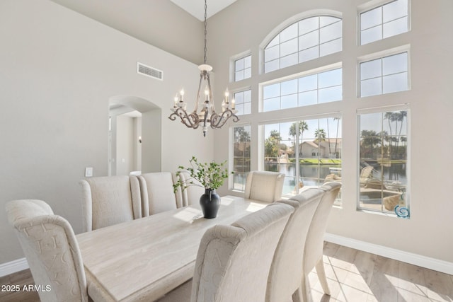 dining space featuring arched walkways, wood finished floors, visible vents, and baseboards