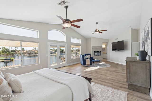 bedroom featuring visible vents, a glass covered fireplace, light wood-style flooring, access to outside, and french doors