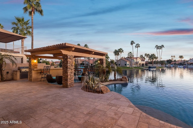 pool at dusk with a patio, a water view, exterior kitchen, a residential view, and a pergola