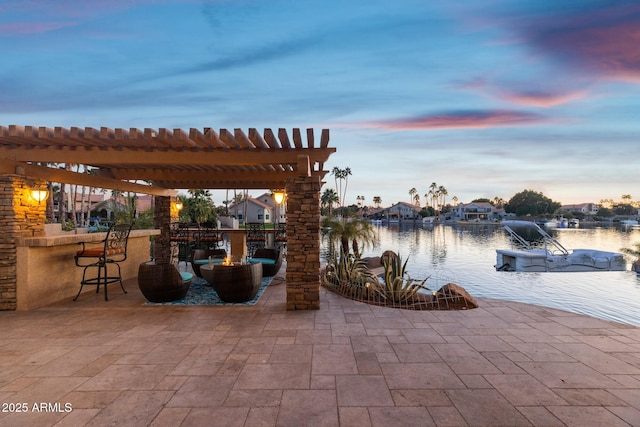 patio terrace at dusk with a water view and a pergola