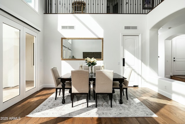 6556 N Arizona Biltmore Cir, Phoenix, AZ 85016 - dining room with visible vents, wood finished floors, arched walkways, and a towering ceiling
