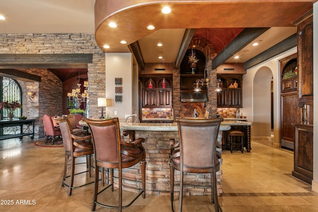 bar featuring arched walkways, recessed lighting, and wet bar