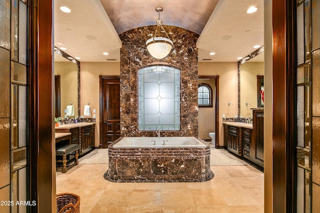 full bath with a garden tub, vaulted ceiling, vanity, and toilet