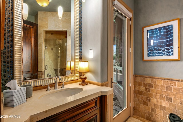 full bathroom with a shower stall, vanity, and tile walls