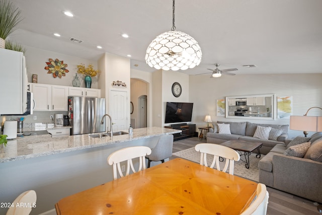 dining space featuring vaulted ceiling, sink, ceiling fan, and light wood-type flooring