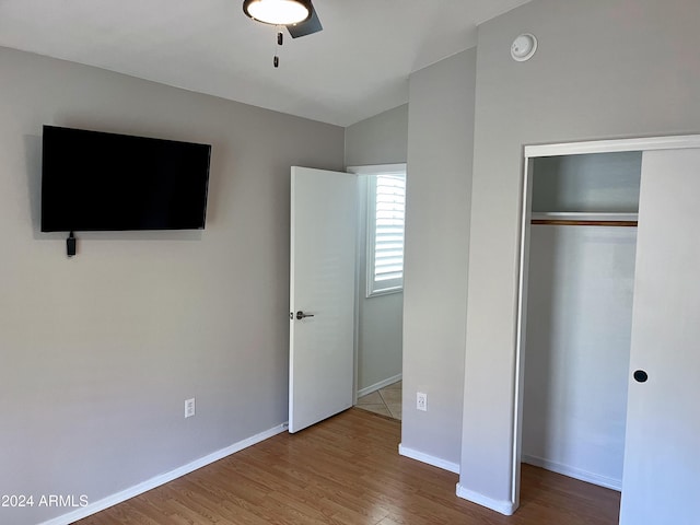 unfurnished bedroom with ceiling fan, lofted ceiling, wood-type flooring, and a closet