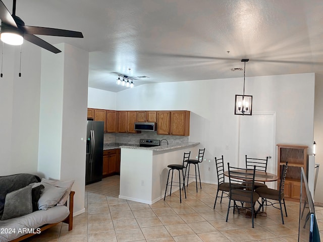 kitchen with hanging light fixtures, stainless steel appliances, kitchen peninsula, track lighting, and a kitchen bar