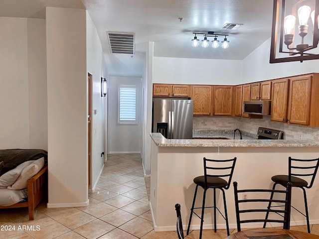 kitchen with stainless steel appliances, backsplash, kitchen peninsula, lofted ceiling, and a kitchen bar