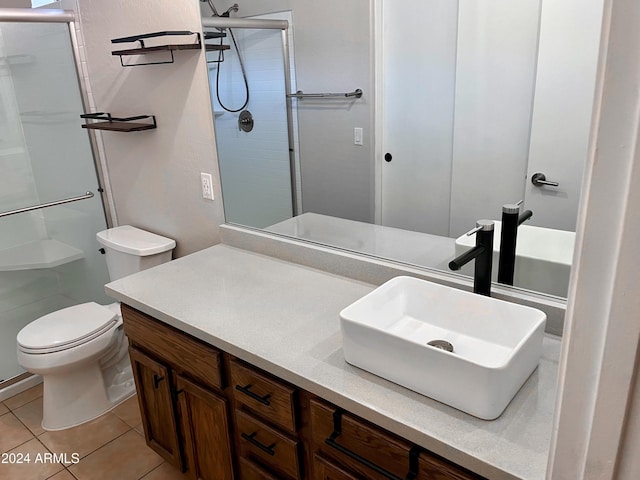 bathroom featuring toilet, vanity, tile patterned floors, and a shower with shower door