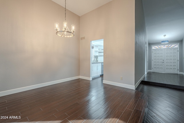 spare room with a chandelier, high vaulted ceiling, dark wood-type flooring, and sink