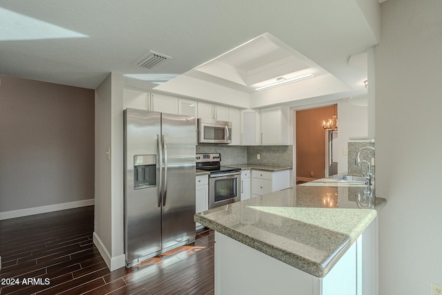 kitchen with kitchen peninsula, light stone counters, white cabinets, and appliances with stainless steel finishes