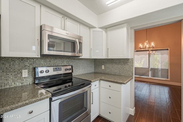 kitchen featuring white cabinetry, dark wood-type flooring, stainless steel appliances, an inviting chandelier, and decorative backsplash