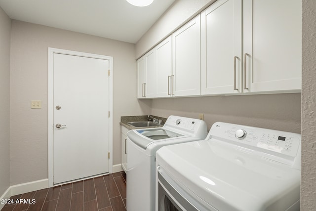 clothes washing area with cabinets, dark wood-type flooring, washer and dryer, and sink