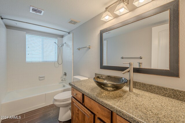 full bathroom with vanity, tiled shower / bath combo, a textured ceiling, wood-type flooring, and toilet