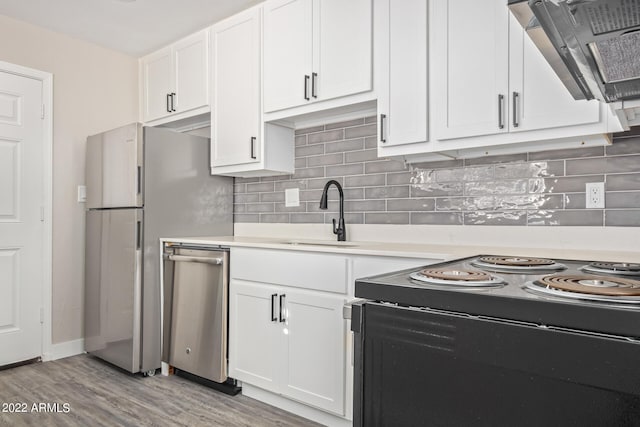 kitchen featuring stainless steel dishwasher, light hardwood / wood-style floors, wall chimney range hood, white cabinetry, and sink