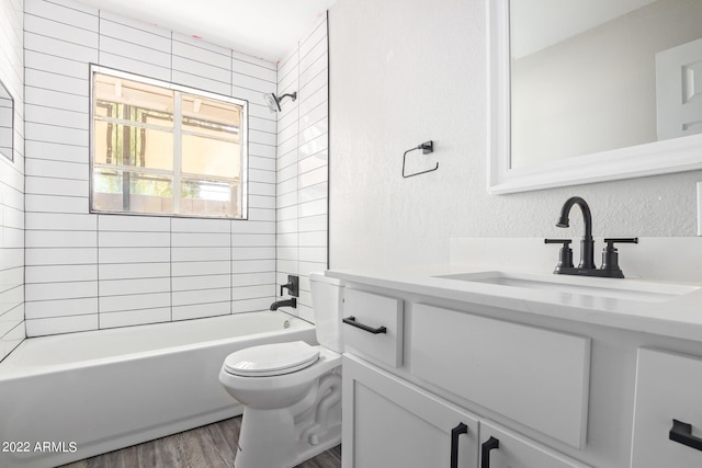 full bathroom with tiled shower / bath, toilet, vanity, and hardwood / wood-style floors