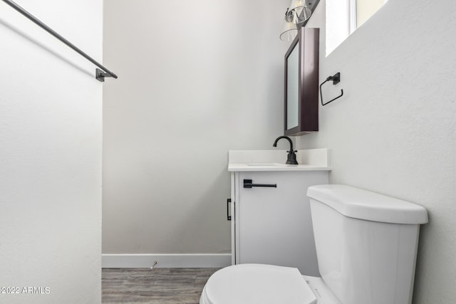 bathroom with toilet, hardwood / wood-style flooring, and vanity