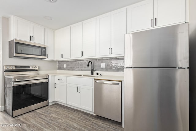 kitchen with tasteful backsplash, stainless steel appliances, sink, hardwood / wood-style flooring, and white cabinets