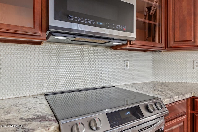 kitchen featuring decorative backsplash, stainless steel appliances, and light stone countertops