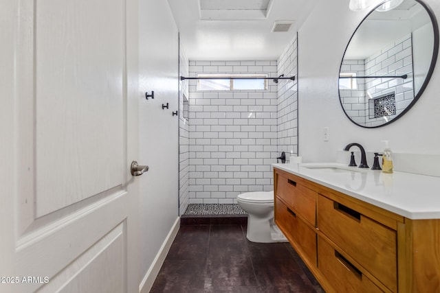 bathroom featuring toilet, vanity, and tiled shower