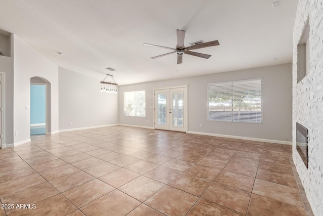 unfurnished living room with a wealth of natural light, a fireplace, light tile patterned floors, and ceiling fan