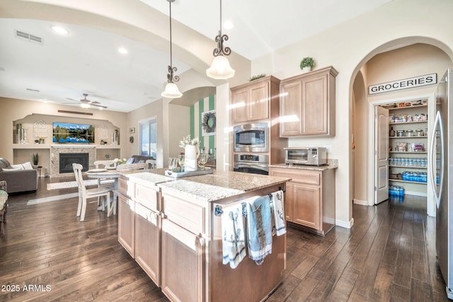 kitchen featuring light stone countertops, decorative light fixtures, dark hardwood / wood-style flooring, stainless steel appliances, and ceiling fan