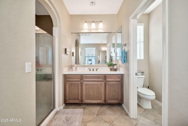 bathroom featuring toilet, tile patterned floors, walk in shower, and vanity