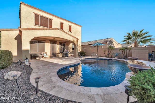 view of pool with grilling area and a patio