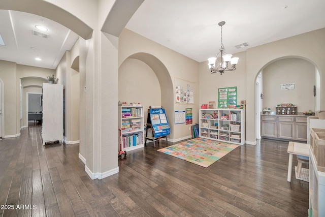 game room with dark wood-type flooring and a notable chandelier