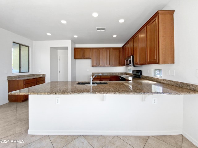 kitchen featuring black electric range, light stone countertops, sink, a kitchen breakfast bar, and kitchen peninsula