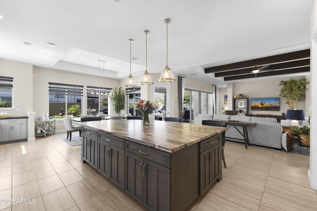 20795 W San Juan Ave, Buckeye, AZ 85396 - kitchen featuring light tile patterned floors, a tray ceiling, dark brown cabinetry, a center island, and decorative light fixtures