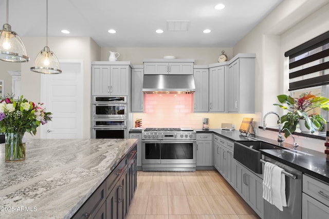 20795 W San Juan Ave, Buckeye, AZ 85396 - kitchen featuring appliances with stainless steel finishes, under cabinet range hood, a sink, backsplash, and dark stone countertops