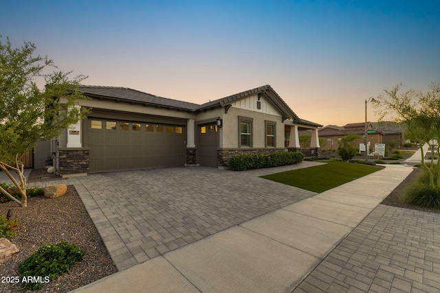 20795 W San Juan Ave, Buckeye, AZ 85396 - craftsman inspired home with stone siding, a garage, decorative driveway, a yard, and stucco siding