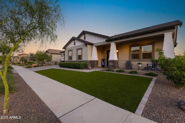 20795 W San Juan Ave, Buckeye, AZ 85396 - craftsman-style house with covered porch, stone siding, a yard, stucco siding, and board and batten siding