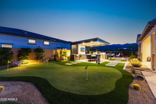 20795 W San Juan Ave, Buckeye, AZ 85396 - yard at dusk featuring a putting green, a fenced backyard, and a patio area
