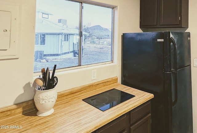 kitchen featuring electric panel, black appliances, and dark brown cabinets