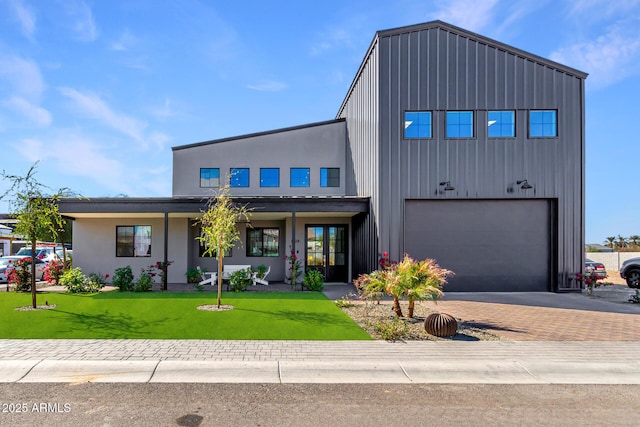 view of front facade with a garage, board and batten siding, decorative driveway, and a front yard