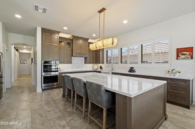 5332 E Thunder Hawk Rd, Cave Creek, AZ 85331 - kitchen featuring double oven, arched walkways, decorative backsplash, a kitchen island, and recessed lighting