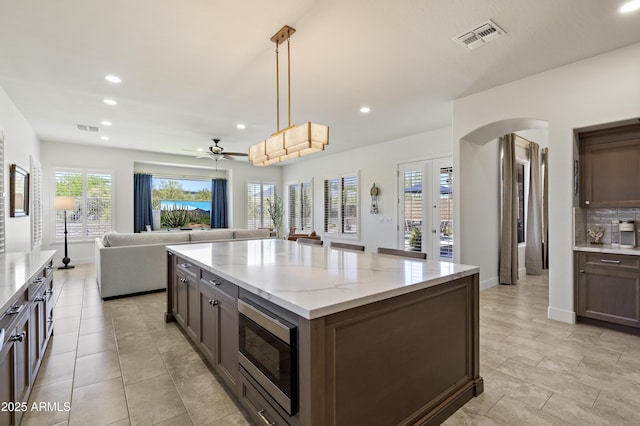 5332 E Thunder Hawk Rd, Cave Creek, AZ 85331 - kitchen with stainless steel microwave, arched walkways, open floor plan, ceiling fan, and recessed lighting