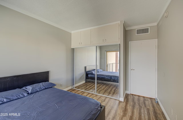 bedroom with visible vents, a textured ceiling, light wood-type flooring, and baseboards