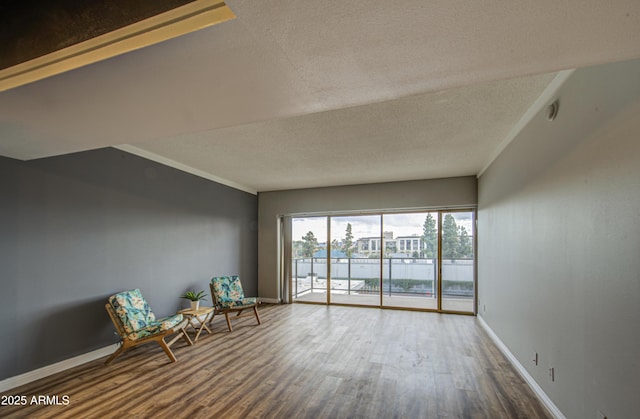 unfurnished room with wood finished floors, baseboards, and a textured ceiling